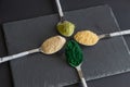 Four spoons with superfood powders, spirulina, matcha tea, maca, ginger on stone board. View from top, superfood supplements