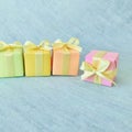 Four square gift boxes in rainbow colors are arranged in a row, one is stands out on light blue texture background. Royalty Free Stock Photo