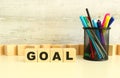 Four stacked wooden cubes with the letters GOAL on a white desktop on a gray background.