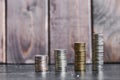 Four stacks of coins on a wooden background in the form of an ascending graph Royalty Free Stock Photo