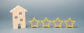 Four stars and a wooden house on a gray background. Success. Feedback. Good evaluation of the critic. Hotel rating. Quality of Royalty Free Stock Photo