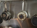 Four steel saucepans with burnt bottoms hanging in industrial kitchen