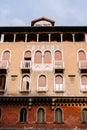 A four-story brown brick building in Venice, Italy. Narrow arched windows, with small balconies with columns, brown Royalty Free Stock Photo