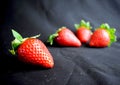 Four strawberries on black fabric