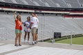 Four students remove their protective face masks to pose for a selfie in front of the empty UGA football stadium