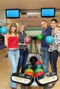 Four students stand near tenpin bowling with balls