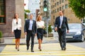 Four successful business people crossing the street in the city