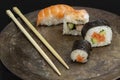 Four sushi rolls on a dark metal plate, with chopsticks Royalty Free Stock Photo