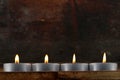 Four tealights, candles on dark wooden background Royalty Free Stock Photo