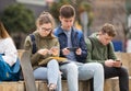 Four teenagers enthusiastically look at the screens of their smartphones on street