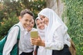 four teenagers in junior high school uniforms using and looking at cellphones