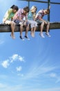 Four teenagers sitting on wooden bridge against blue sky Royalty Free Stock Photo