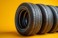 Four tires lined up in a row against a vibrant yellow background. Generative AI Royalty Free Stock Photo