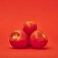 Four tomatoes on a scarlet red background