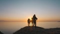 The four tourists walking near the sea on the beautiful sunset background.