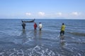 Four traditional fishermen on Alue Naga beach, Banda Aceh, Indonesia, walk to the boat to pull the trawl