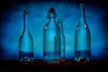 Four transparent glass bottles on a barn wood table in front of a blue background Royalty Free Stock Photo
