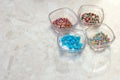 Four transparent glass cups with decorations for confectionery and baking on the marble background.