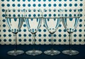 Four transparent glasses for wine standing in line and white background with blue spots.
