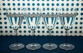 Four transparent wine glasses standing in line and white background with blue spots.