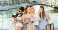 Four traveling young people searching for direction using paper map on waterfront in town