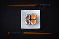 Four tuna salmon maki sushi and chopstick on black