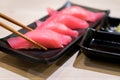 Four tuna sushi with chopsticks in black plate on table at Japanese restuarant. Royalty Free Stock Photo