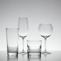 Four types of clear glassware are displayed on a reflective surface: a tall cylindrical Royalty Free Stock Photo