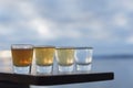 Four types of tequila shots lined up on seaside deck
