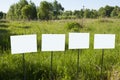 Four unfilled posters stand in the field along