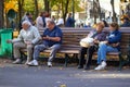 Four unidentified happy retired people rest on a bench, autumn scene