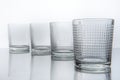Four water glasses on neutral glass background
