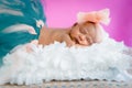 Four weeks baby infant girl studio photo sleeping on fluffy pillow wearing tutu and bow