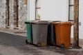 Four wheelie bins of different color and waste left in a street for collection. Waste and recycle management industry