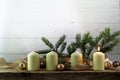 Four white candles, one of them burning on the first advent christmas decoration with spruce twigs, baubles and a golden ribbon o Royalty Free Stock Photo