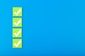 Four white checkmarks on green tablets in a row against blue background with copy space