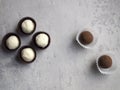 Four white coconut candies in brown wrappers and two brown chocolate truffles in white candy wrappers on a gray background. Royalty Free Stock Photo