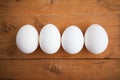 Four white eggs on the wooden background