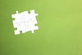 Four white jigsaw pieces fitted together to form a group joined on all sides. green background. copy space. working set. space for Royalty Free Stock Photo