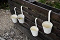 Four white metal cups hanging on a wooden stillage Royalty Free Stock Photo