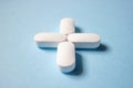 Four white pills are stacked in the form of a medical cross on a blue background Royalty Free Stock Photo