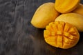 Four whole mango fruits on wooden table and cut into slices. Large yellow fruits , copy space