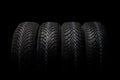 Four winter tires isolated on black background