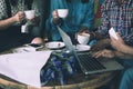 Four women do meeting by sharing information from notebook and drinking coffee in coffee shop with warm light flare tone