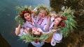 Four women in floral circlets standing in water