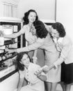 Four women taking things from a refrigerator