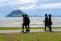 Four women in twos walking along harbourside walkway with Mount Maunganui in background