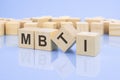 four wooden blocks with the letters MBTI on the bright surface of a pale lilac background. the inscription on the cubes