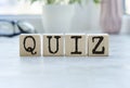 Four wooden blocks with the letters QUIZ on the bright surface of a pale lilac table. the inscription on the cubes is reflected