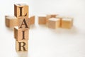 Four wooden cubes arranged in stack with text LAIR meaning Listen, Acknowledge, Identify, Reversal on them, space for text /